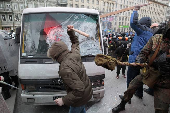 Protesters attack a riot police bus in central Kiev, Ukraine, Sunday, Jan. 19, 2014. Hundreds of protesters on Sunday clashed with riot police in the center of the Ukrainian capital, after the passage of harsh anti-protest legislation last week seen as part of attempts to quash anti-government demonstrations. A group of radical activists began attacking riot police with sticks, trying to push their way toward the Ukrainian parliament building, which has been cordoned off by rows of police and buses.