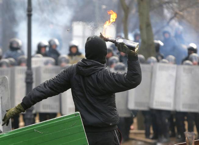 A protester throws a Molotov cocktail during unrest in central Kiev, Ukraine, Monday, Jan. 20, 2014. After a night of vicious streets battles, anti-government protesters and police clashed anew Monday in the Ukrainian capital Kiev. Hundreds of protesters, many wearing balaclavas, hurled rocks and stun grenades and police responded with tear gas.
