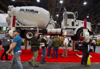 Attendees walk about a mixer above them from a Stertil Koni lift during the 40th anniversary of the World Of Concrete event at the Las Vegas Convention Center on Wednesday, Jan. 22, 2014.