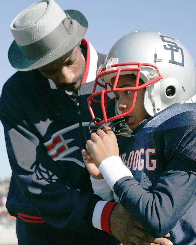 Rap artist and actor Snoop Dogg, left, talks to his son Cordell Broadus, 7, a member of the the Snoop All-Stars youth football team, before their game against the Jacksonville All-Stars in Snoop Bowl at Raines High School in Jacksonville, Fla., Saturday, Feb. 5, 2005. 