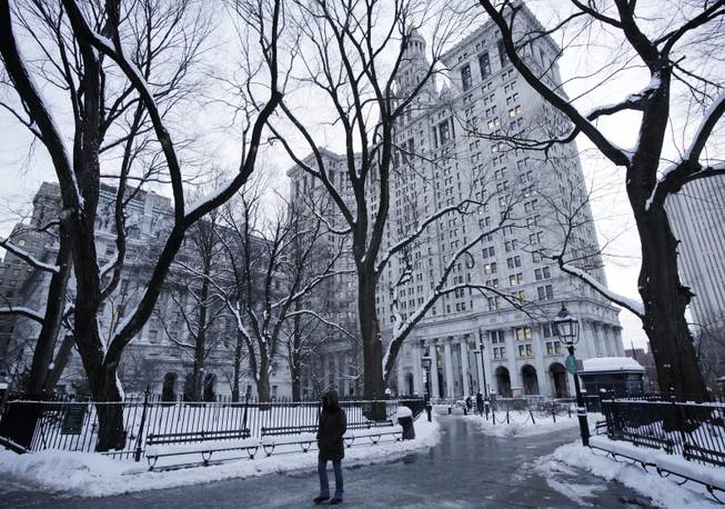 A pedestrian passes through City Hall Park and the Municipal Building, center, Wednesday, Jan. 22, 2014, in New York. The Northeast struggled to dig out of a winter storm Wednesday that swirled up the coast, disrupting government work in Washington and leaving behind bitter cold that sapped fuel supplies. 