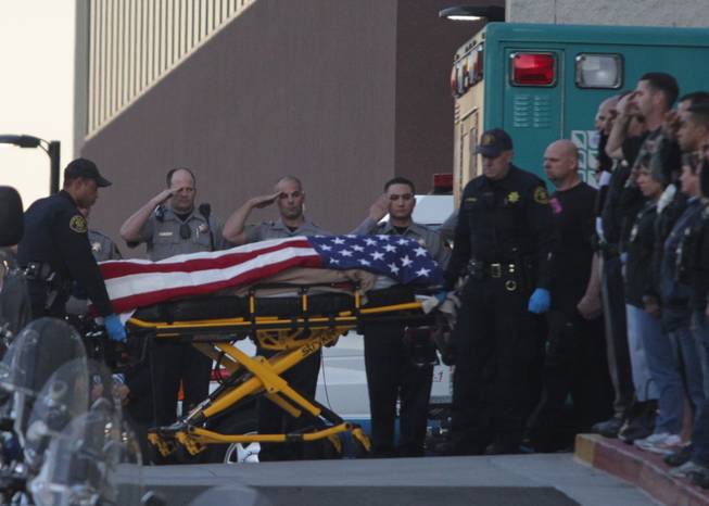 Law enforcement officers salute as the body of a Bay Area Rapid Transit police officer draped with the American flag is loaded into an Alameda County Sheriff's Coroner vehicle at Eden Medical Center in Castro Valley, Calif., Tuesday, Jan. 21, 2014. The officer was shot while serving a probation search warrant at a residence in Dublin, Calif., according to authorities.