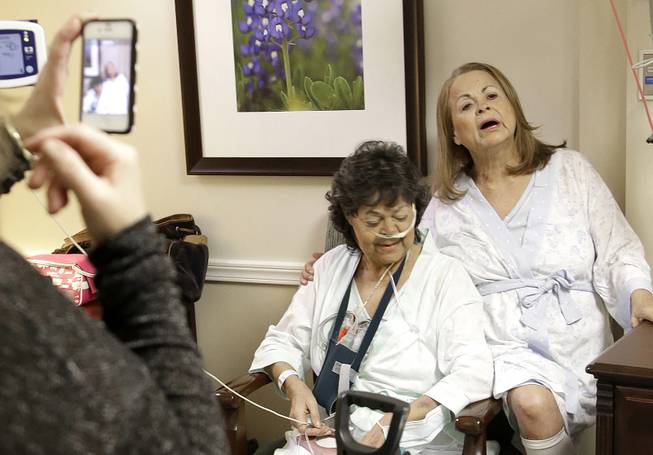 Irma Myers-Santana, left, and her sister Anna Williamson, right, sing a song as Kim Pappas films them with her cellphone in Houston, Jan. 14, 2014. Earlier this month the sisters ended up in the same operating room, each getting one lung from the same donor.