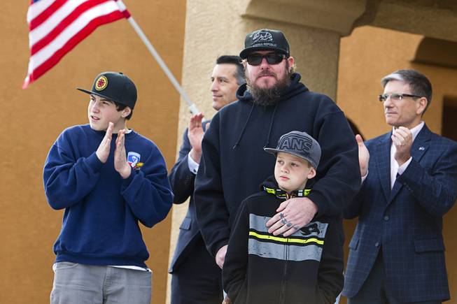 Army Sgt. Christopher Bales, center, and his sons Keenan, 14, and Aiden, 8, listen to speakers during a new home dedication in the Mountain's Edge master-planned community Thursday Jan. 23, 2014. In the background are Nevada Governor Brian Sandoval, left, and Congressman Joe Heck (R-NV). 