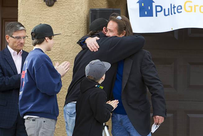 Stephen Page, right, USAF director of corporate sponsorship for Operation Finally Home, gives a hug to Army Sgt. Christopher Bales during a new home dedication for Bales and his family at the Coldwater Crossing subdivision in the Mountain's Edge master planned community Thursday Jan. 23, 2014. Pulte Homes, along with other companies, presented the home to Bales as part of Operation Finally Home," an organization which provides homes to veterans and the families of fallen servicemen.