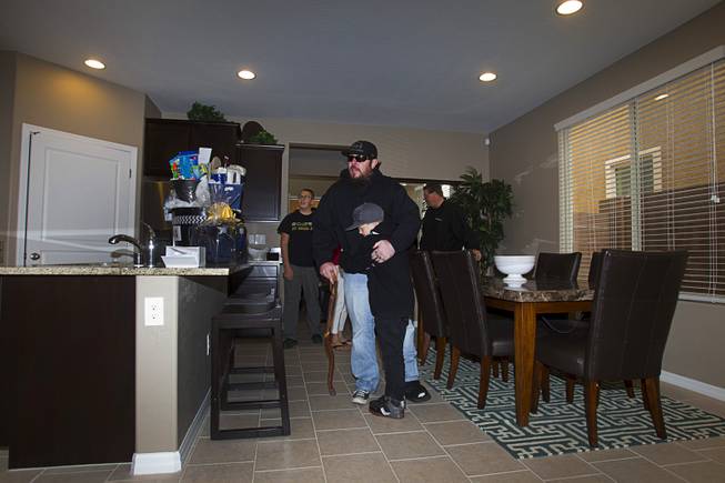 Army Sgt. Christopher Bales and his son Aiden, 8, get a look at the inside of his new home at the Coldwater Crossing subdivision in the Mountain's Edge master planned community Thursday Jan. 23, 2014. Bales was shocked to discover that the home was completely furnished. Pulte Homes, along with other companies, presented the home to Bales as part of Operation Finally Home," an organization which provides homes to veterans and the families of fallen servicemen.