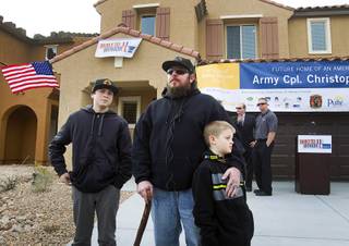 Army Sgt. Christopher Bales, center, and his sons Keenan, 14, and Aiden, 8, talk with reporters in front of their new home at the Coldwater Crossing subdivision in the Mountain's Edge master planned community Thursday Jan. 23, 2014. Pulte Homes, along with other companies, presented the home to Bales as part of Operation Finally Home,