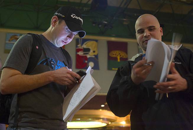 Matt Emanuel, left, of Charlotte, N.C. waits in line to place a bet on Super Bowl XLVIII at the Las Vegas Hotel Superbook Thursday Jan. 23, 2014.