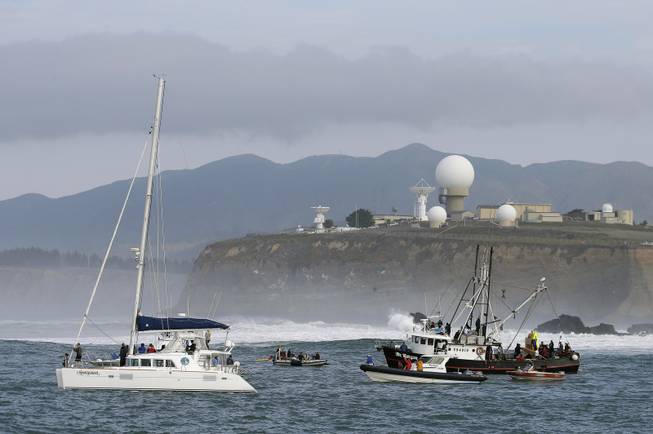People on boats watch the third heat of the first round of the Mavericks Invitational big wave surf contest with the Pillar Point Air Force Station in the background Friday, Jan. 24, 2014, in Half Moon Bay, Calif.