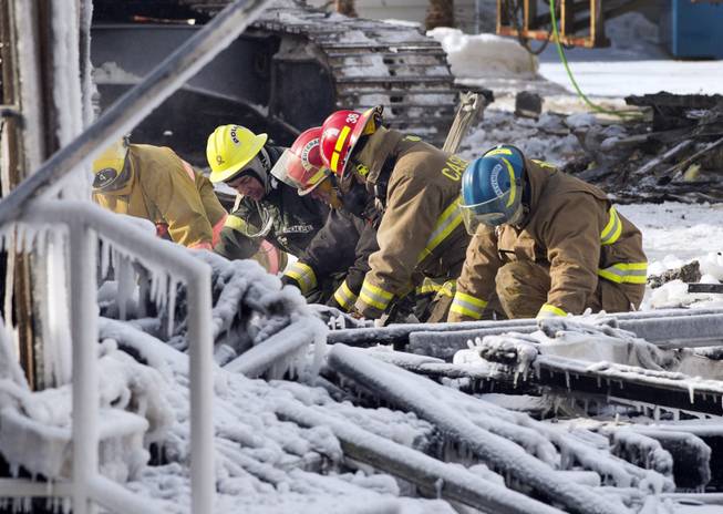 Rescue personnel search through the icy rubble of deadly fire that destroyed a seniors' residence Friday, Jan. 24, 2014, in L'Isle-Verte, Quebec.