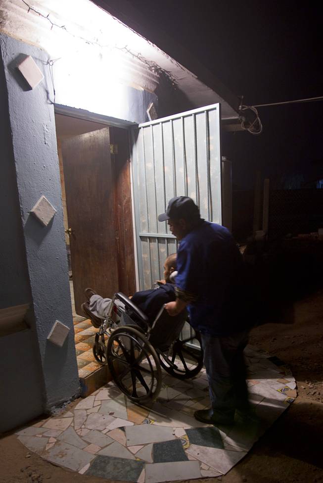 Assistant Jose Alberto Ramirez takes Francisco Diaz back inside a elderly care home in Mexicali, Mexico Saturday, Jan. 25, 2014. Diaz was born in Mexico but grew up in Las Vegas with a green card. Diaz was beaten and robbed after he was deported to Mexicali.