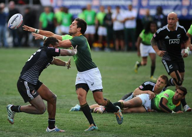 South African Springbok 7's player Stephan Dippenaar, right, passes the ball as he is hit by New Zealand All Blacks 7's Lote Raikabula (left) during the Cup Final match of the USA 7's rugby tournament at Sam Boyd Stadium on Sunday afternoon. South Africa won the match 14-7.