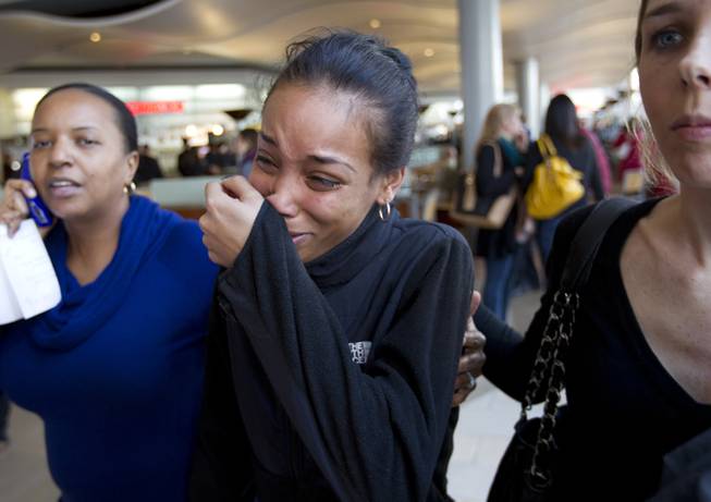 Courtney, center, a friend of one of the victims in Saturday's shooting at the Mall in Columbia, Md,, cries as she walks through the food court with friends after the mall was reopened to the public on Monday Jan. 27, 2014.