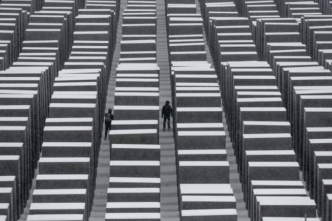 Two visitors walk inside the snow covered Holocaust Memorial at the International Holocaust Remembrance Day in Berlin, Monday, Jan. 27, 2014. The German parliament Bundestag will hold a special remembrance session at the Reichstag building in commemoration of the liberation of the Auschwitz death camp on Jan. 27, 1045.