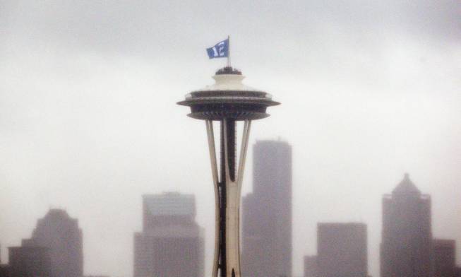 A "12th Man" flag, honoring Seattle Seahawks fans, is barely visible as it flutters atop the Space Needle in the rain Wednesday, Jan. 29, 2014, in Seattle. The Seahawks play the Denver Broncos in Super Bowl XLVIII on Sunday.