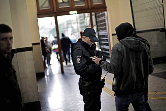 A police officer checks the identification of a passerby in the central train station, Wednesday, Jan. 29, 2014, in Sochi, Russia, home of the upcoming 2014 Winter Olympics.