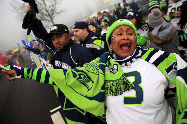 Marcia Shiri-Wasto, center, cheers with Seattle football fans on South 188th Street in SeaTac, Wash. Sunday, Jan. 26, 2014. The Seahawks drove past the crowd on route to the airport for Super Bowl XLVIII. 
