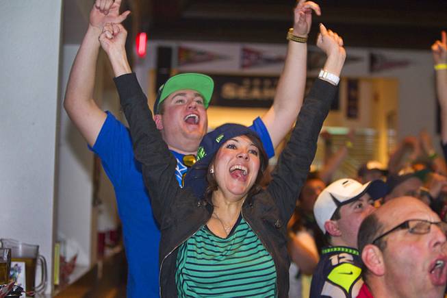 Seattle Seahawks fans Ashley Schamp, of Las Vegas,  and her boyfriend Eric Leipper, originally of Seattle, cheer a pass completion as they watch Super Bowl XLVIII from Scooters Pub, 6200 S. Rainbow Blvd., Sunday, Feb. 2, 2014.