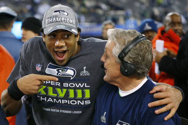 Seattle Seahawks quarterback Russell Wilson laughs with Seahawks head coach Pete Carroll during a TV interview after Super Bowl XLVIII on Sunday, Feb. 2, 2014, in East Rutherford, N.J. The Seahawks defeated the Denver Broncos 43-8.