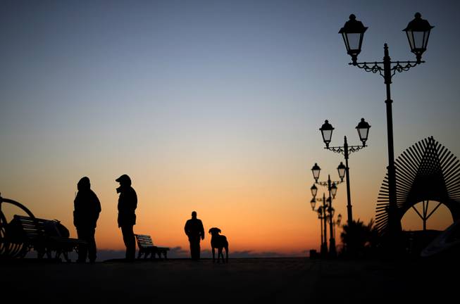 Police patrol along the boardwalk on the Black Sea accompanied by a stray dog outside the Olympic Park at the 2014 Winter Olympics, Monday, Feb. 3, 2014, in Sochi, Russia. 