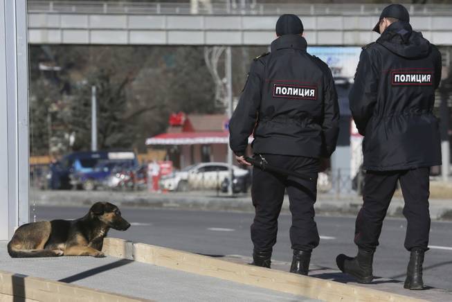 Policemen walk past a stray dog near the Media Center of the 2014 Winter Olympics, Monday, Feb. 3, 2014, in Krasnaya Polyana, Russia.