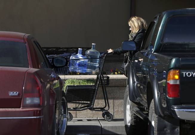 In this photo taken Tuesday, Feb. 4, 2014,  Kathleen Camp leaves a local market with bottled water in Willits, Calif.  With area reservoirs holding less than a 100-day supply of water, city leaders have banned lawn watering, car washing and mandated all residents to cut water use.