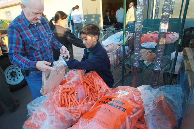 Volunteers Steve Wildman, left, and Luke Mathews portion our bags of carrots to be given away at Our Savior Church's food line Wednesday, Feb. 5, 2014 in Henderson.