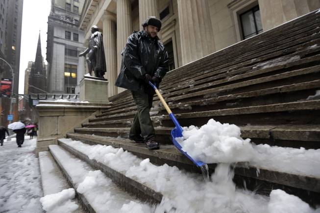 U.S. Parks Service employee Danny Merced clears snow from the steps of Federal Hall, in New York's Financial District, Wednesday, Feb. 5, 2014.  New York City's sanitation commissioner says some secondary streets still need plowing but overall snow removal was going well. Around 6 inches of snow are expected in parts of the metropolitan area on Wednesday.