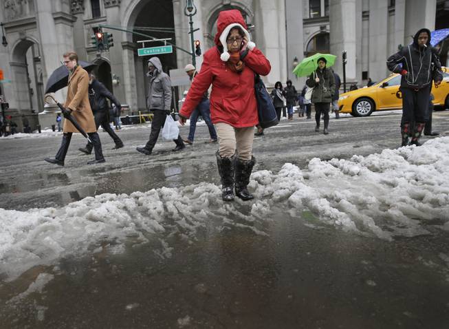 Pedestrians make their way through a slushand water at an intersection in New York, Wednesday, Feb. 5, 2014. Around 6 inches of snow are expected in parts of the metropolitan area on Wednesday.