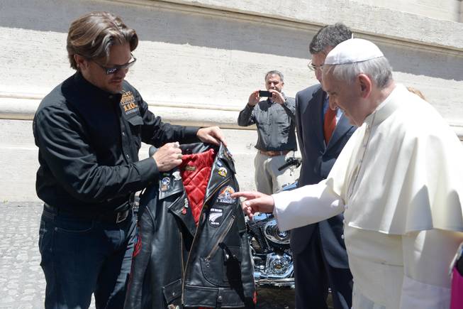In this June 12, 2013, file photo provided by the Vatican paper L'Osservatore Romano, Pope Francis receives a leather jacket from Harley Davidson Motor Company senior vice-president Mark Hans-Richer, at the Vatican. A 1,585cc Harley-Davidson Dyna Super Glide, donated to Pope Francis last year and signed by him on its tank, will be sold at auction in Paris to help raise funds for a soup kitchen and hostel for the homeless in Rome.
