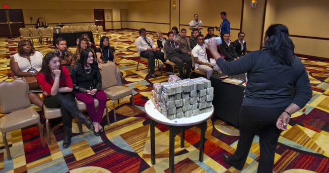 With a stack of $140,000, Finance Dept. Controller Ramona Lockett talks to Desert Rose Adult High School students participating in the National Job Shadow Day about counterfeit bills at the New York-New York Thursday, Feb. 6, 2014.
