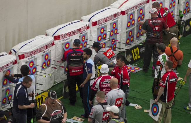 Archers mark their scores and retrieve arrows during the Adult Freestyle Championship in the South Point Arena as part of the Vegas Round of the 2014 NFAA World Archery Festival on Friday, Feb. 7, 2014.