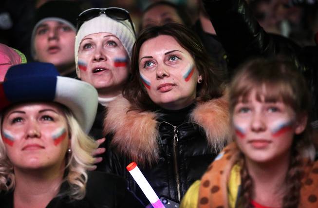 Russian women with their national flag painted on their cheeks watch intensely as the live telecast of the 2014 Winter Olympics opening ceremony is aired, Friday, Feb. 7, 2014, in downtown Sochi, Russia.