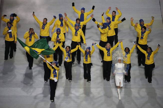 Jaqueline Mourao of Brazil waves her national flag and enters the arena with her team during the opening ceremony of the 2014 Winter Olympics in Sochi, Russia, Friday, Feb. 7, 2014.