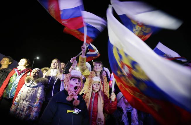 A Russian child yawns while others wave the national flag as the Russian national anthem is played during the live telecast of the 2014 Winter Olympics opening ceremony, Friday, Feb. 7, 2014, in downtown Sochi, Russia.