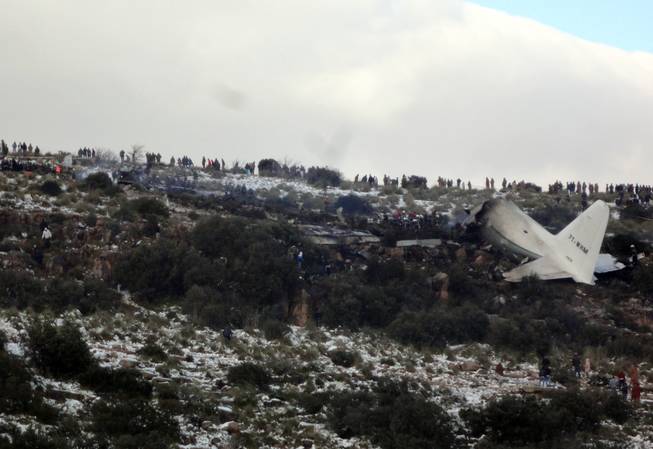 People look at the wreckage of Algerian military transport plane after it slammed into a mountain in the country’s rugged eastern region, Tuesday, Feb. 11, 2014.