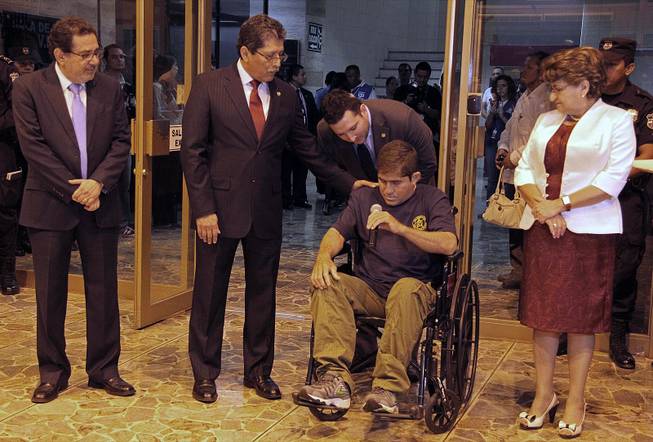 Jose Salvador Alvarenga holds a microphone intending to speak, after arriving at the airport in San Salvador, El Salvador, Tuesday, Feb. 11, 2014. Alvarenga was wheeled in a wheelchair before a crush of more than 100 mostly foreign journalists. But when handed the microphone, he held it in silence.