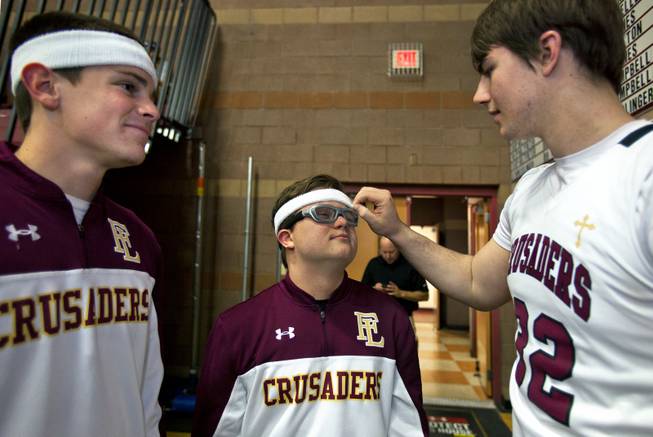 Faith Lutheran senior Clayton Rhodes has a new sweatband adjusted by teammate John Molchon as they prepare on the court for their varsity basketball game against Pahrump on Thursday, Feb. 13, 2014.
