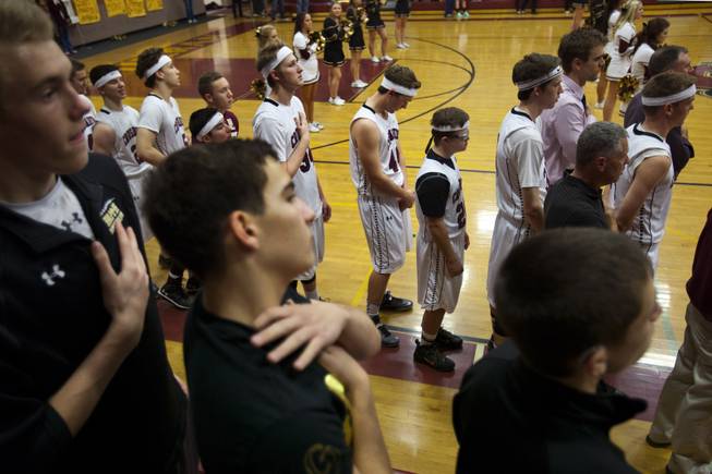 Faith Lutheran varsity basketball players, coaches and fans stand and face the flag for the singing of the "Star Spangled Banner" before the start of their game against Pahrump on Thursday, Feb. 13, 2014.
