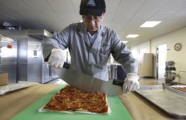 In this Thursday, Feb. 6, 2014 photo, food technologist Tom Yang cuts a prototype pizza at the U.S. Army Natick Soldier Research, Development and Engineering Center, in Natick, Mass. 