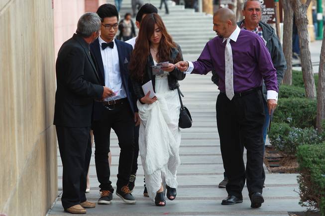 Anthony Mastrangelo, left, and Israel Reyes try to sell Tai Nguyen and Ivy Dinh on their wedding chapel services outside the Marriage Bureau at the Regional Justice Center Friday, Feb. 14, 2014.