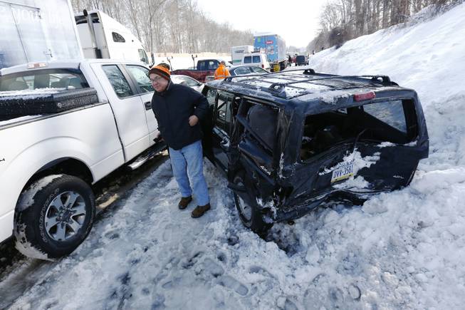 A man gets out of a SUV, one of many vehicles piled up in an accident, Friday, Feb. 14, 2014, in Bensalem, Pa. Traffic accidents involving multiple tractor trailers and dozens of cars have completely blocked one side of the Pennsylvania Turnpike outside Philadelphia and caused some injuries. 