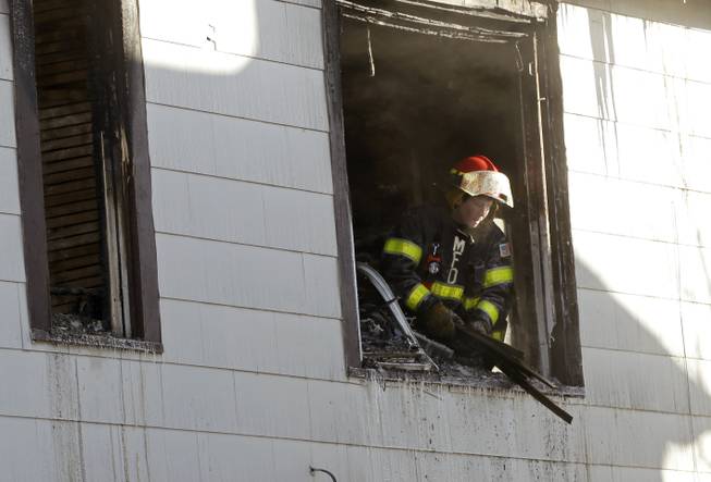 A Minneapolis firefighter throws out debris from the second floor of a North Minneapolis duplex after an early morning fire Friday, Feb. 14, 2014.