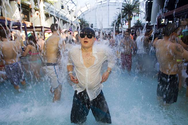 A partygoer, who apparently forgot his swimsuit, cools off under a waterfall during the Halfway to EDC and first winter pool party at Marquee Dayclub on Sunday, Feb. 16, 2014, in the Cosmopolitan of Las Vegas.