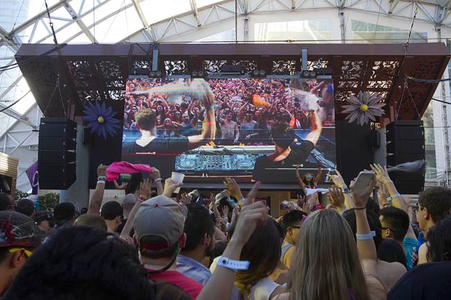 Partygoers listen to electronic dance music by Firebeatz (shown on the video screen) during the Halfway to EDC and first winter pool party at Marquee Dayclub on Sunday, Feb. 16, 2014, in the Cosmopolitan of Las Vegas.
