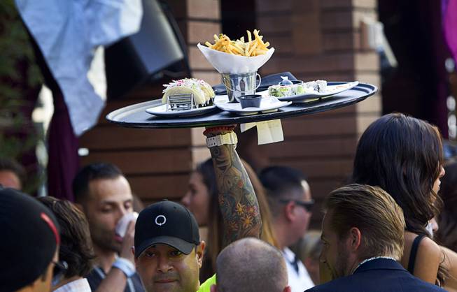 A waiter brings an order of food through the crowded bungalow area during the Halfway to EDC and first winter pool party at Marquee Dayclub on Sunday, Feb. 16, 2014, in the Cosmopolitan of Las Vegas.