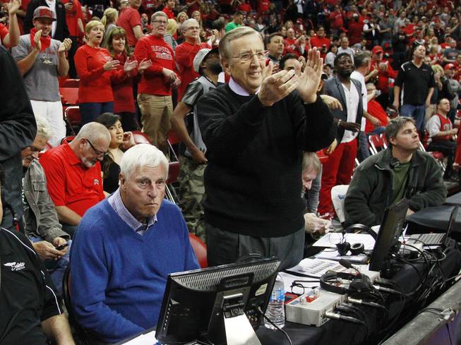 As former UNLV head coach Jerry Tarkanian makes his way across the court to his seat, ESPN broadcaster Brent Musberger joins others at the Thomas & Mack Center in a standing ovation while fellow broadcaster and former Indiana coach Bobby Knight remains seated before the Rebels game against New Mexico Wednesday, Feb. 19, 2014.
