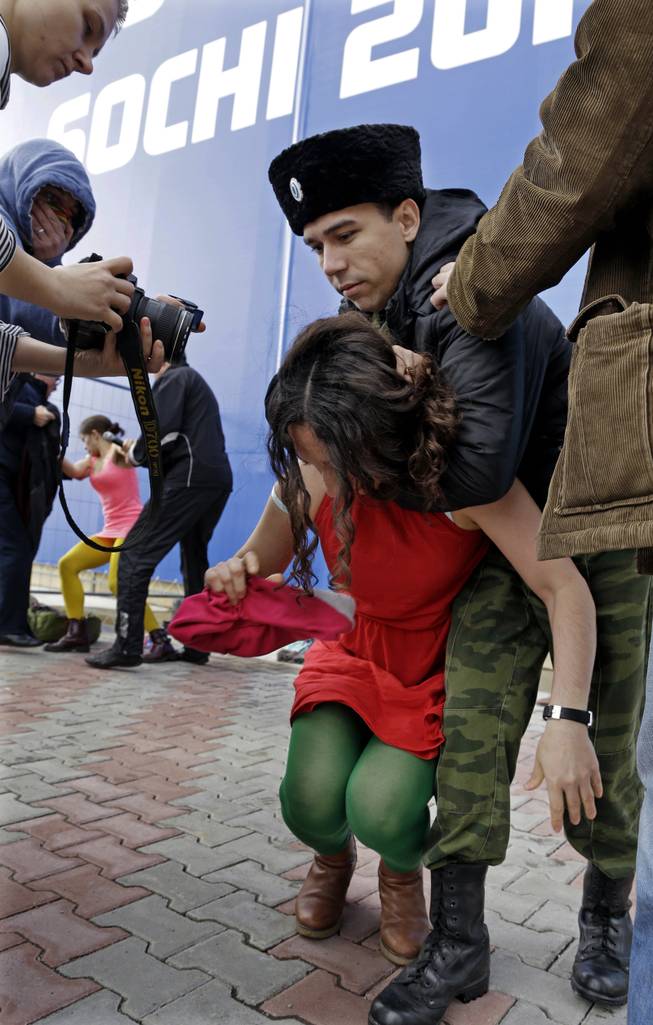 A member of the punk group Pussy Riot is restrained by a member of the Cossack militia  in Sochi, Russia, on Wednesday, Feb. 19, 2014. 