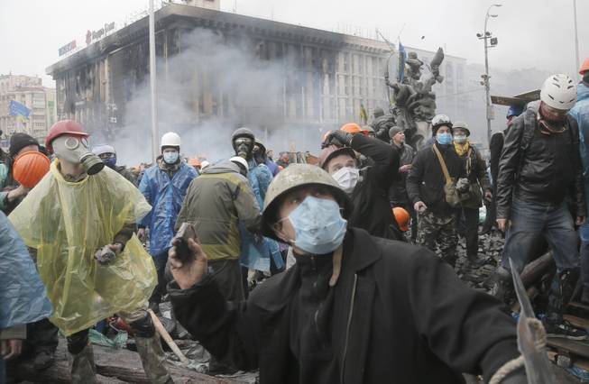 Anti-government protesters throw stones during clashes with riot police in Kiev's Independence Square, the epicenter of the country's current unrest, Kiev, Ukraine, Wednesday, Feb. 19, 2014. 