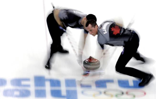 Canada's E.J. Harnden, right, and Ryan Harnden, left, sweep ahead of the rock during the men's curling semifinal game against China at the 2014 Winter Olympics, Wednesday, Feb. 19, 2014, in Sochi, Russia. 